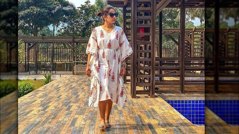 Woman poses in caftan with cinched waist