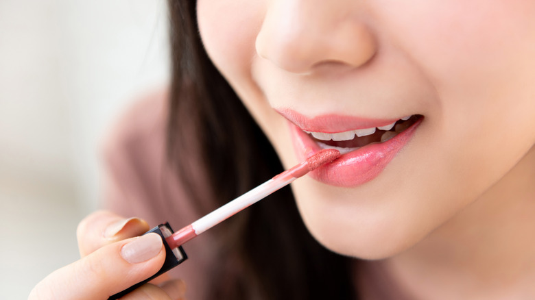 Asian woman applying lipstick