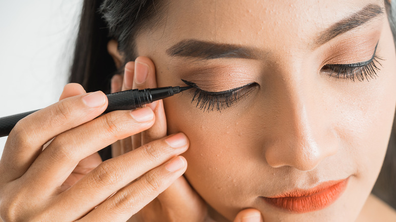 Asian woman applying eyeliner