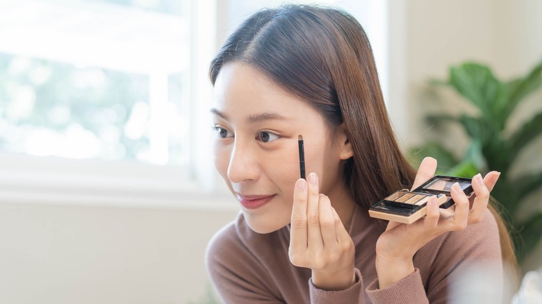 Woman applying makeup on face