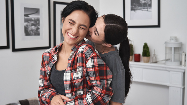 two smiling women hugging flirtatiously