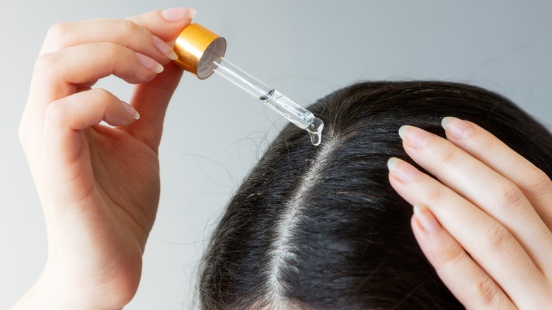 person applying oil to hair
