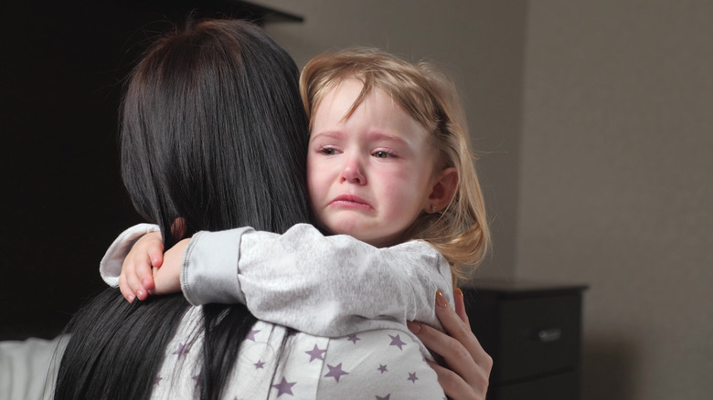 Woman hugs crying little girl 