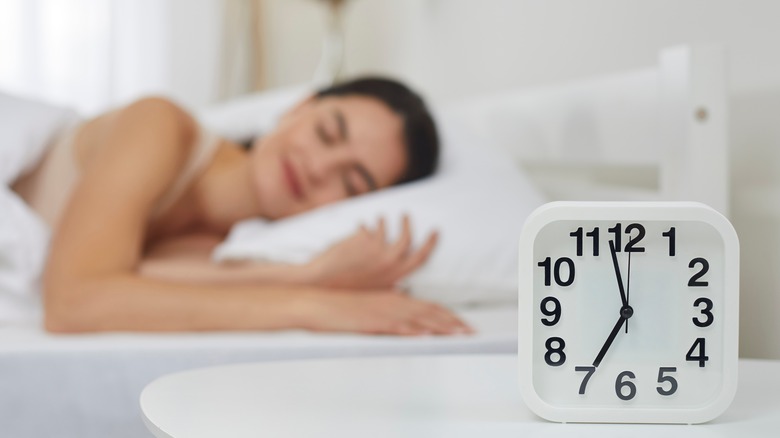 clock next to woman in bed