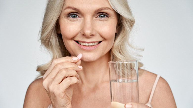 Woman holds probiotic tablet. 