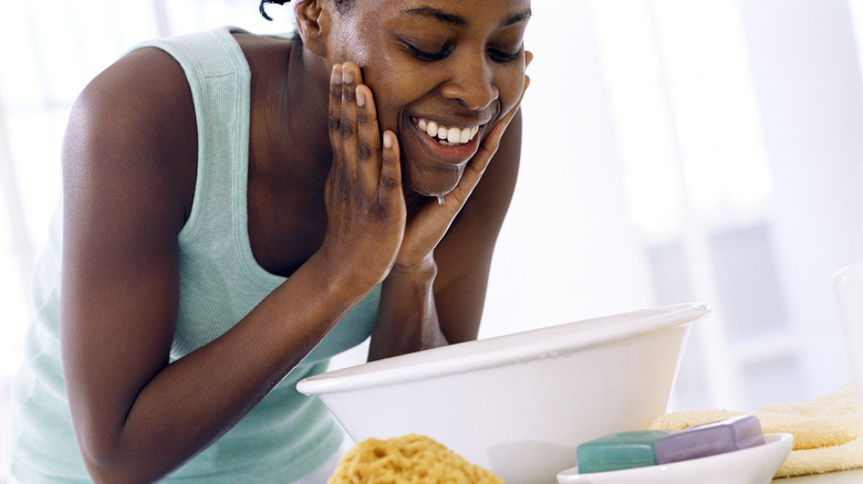 Woman washes face in basin