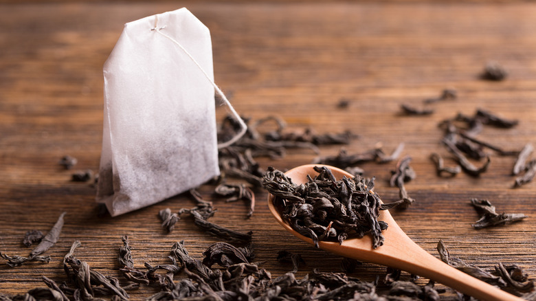 Black tea leaves in a spoon and tea bag