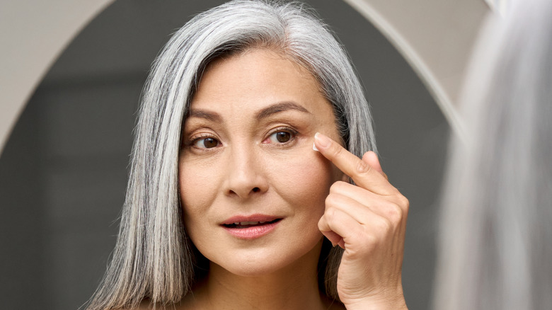 Mature woman applying eye cream