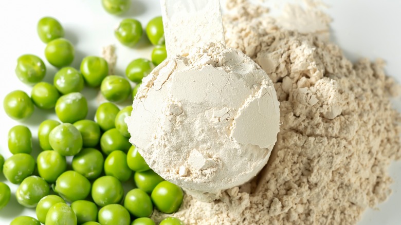 Scoop of plant-based protein powder alongside peas