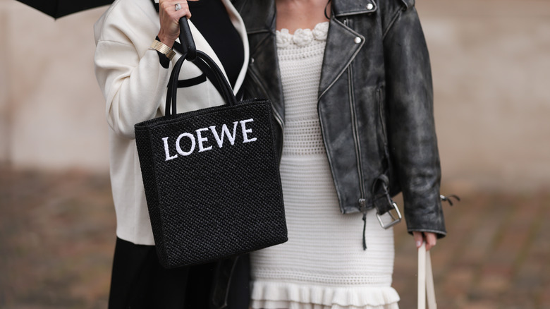 Woman carrying a black raffia tote. 