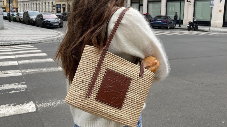 Girl carrying a raffia bag with a sweater on