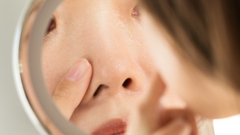 Woman looking at nose in mirror