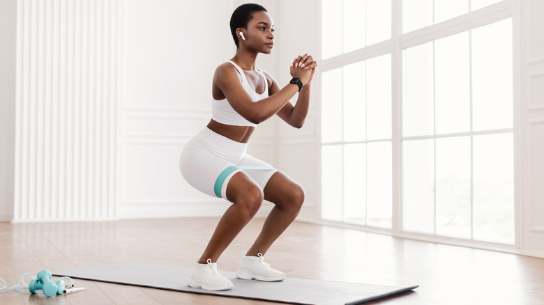 woman squatting on gym mat