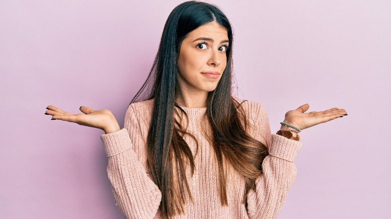 Woman shrugging with purple background