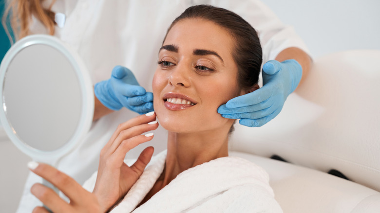 Woman examining results of cosmetic procedure in mirror