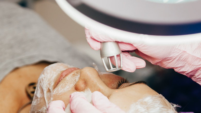 Technician applying laser treatment to patient's face