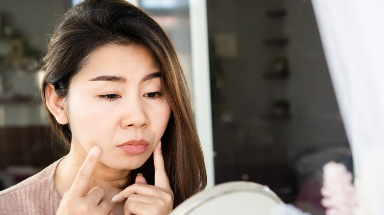 Woman inspecting face in mirror