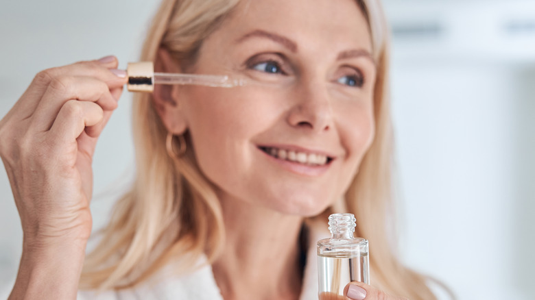 female holding airless serum pump bottle smiling