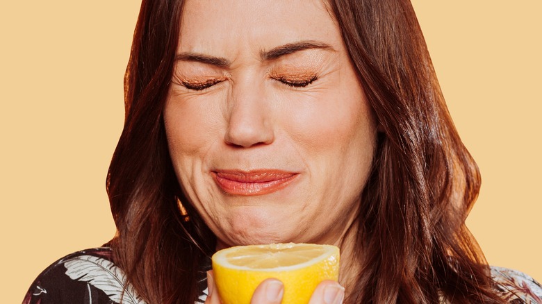 Model making face while eating lemon