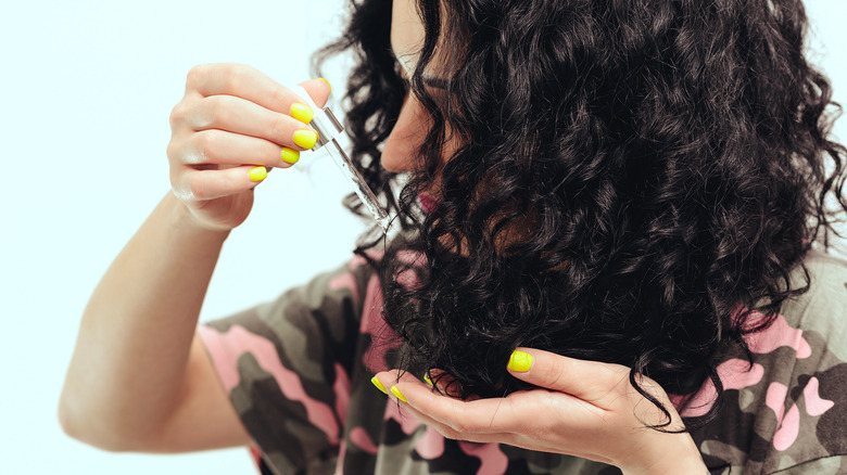 woman with curly hair treats ends with olive oil 