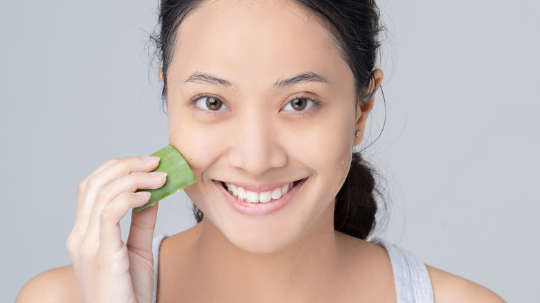 female rubbing aloe vera to face