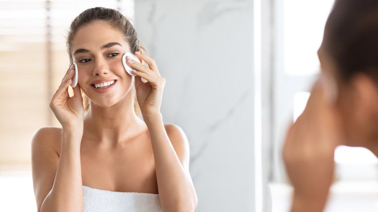 woman rubbing cotton pads on face