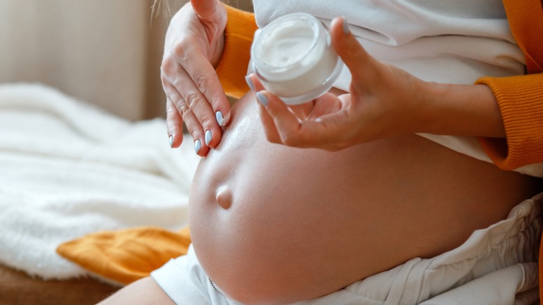 pregnant woman applying cream on her belly