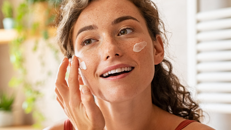 woman apply cream to face