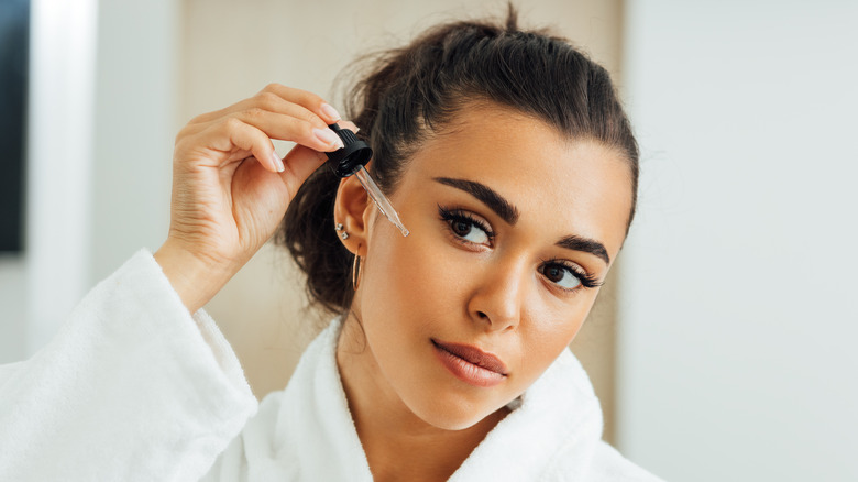 woman applying serum to face