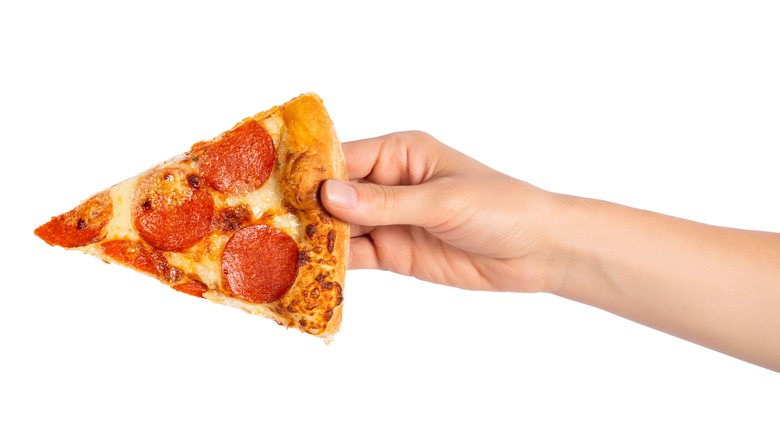 Hand holding pizza slice