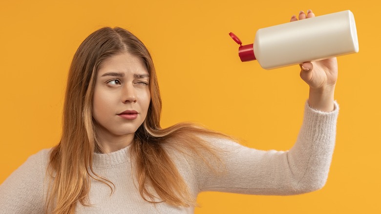 Woman examining shampoo bottle