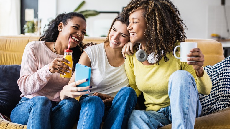 Three friends laughing on a couch 