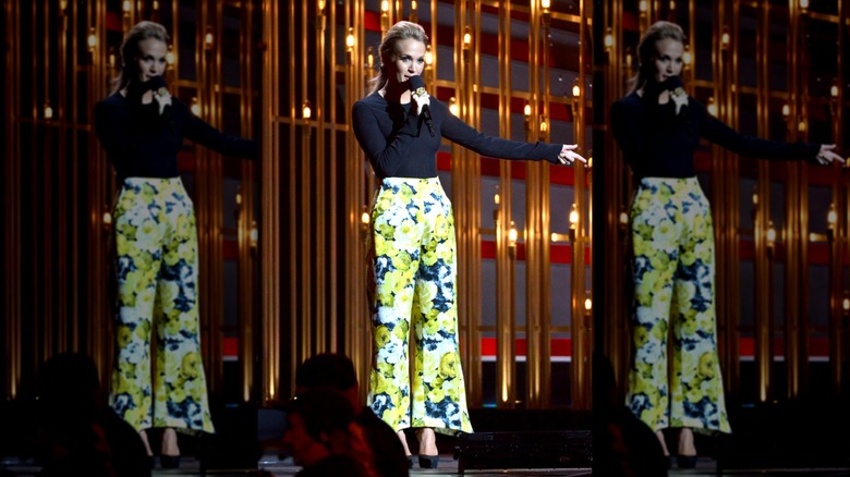 Carrie Underwood wearing a black top and floral slacks while hosting the 2013 CMAs.