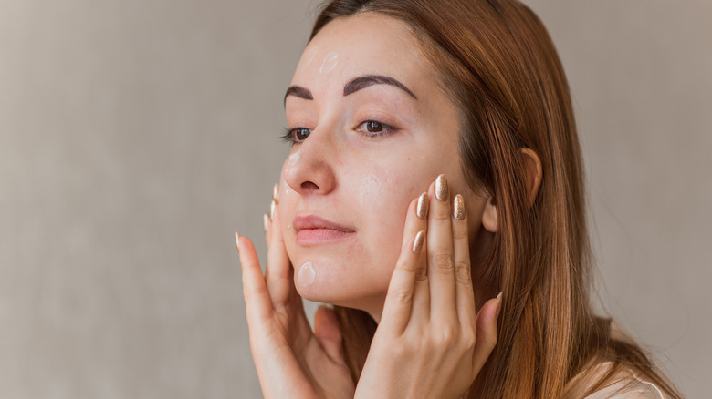 Woman using cream for acne