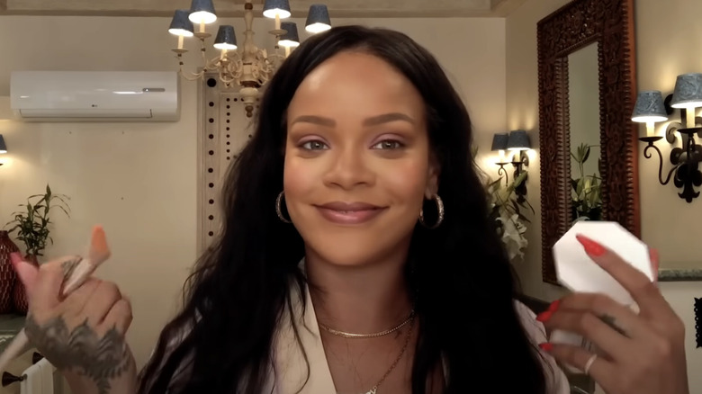 Rihanna smiling during a makeup tutorial shot for Vogue.