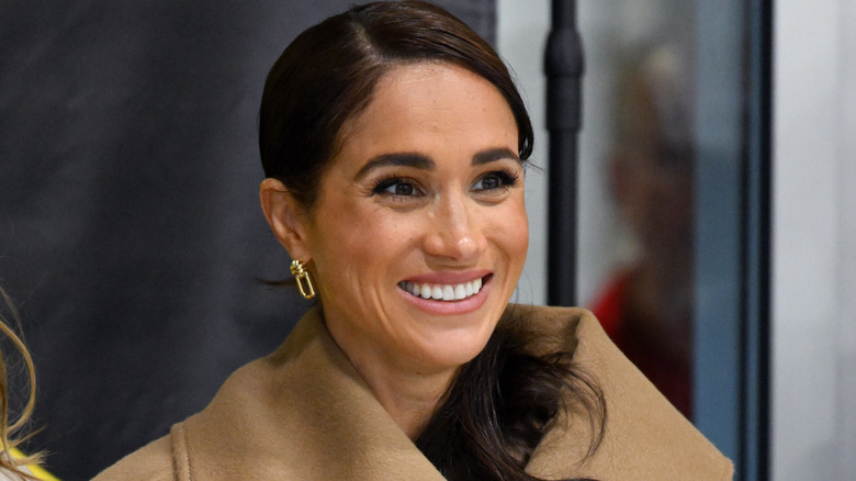 Meghan Markle smiling with her lined lips at an Invictus Games event.