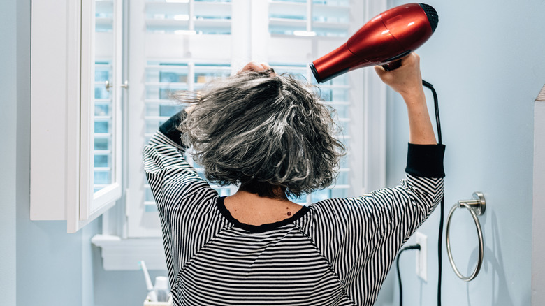 person blow-drying hair