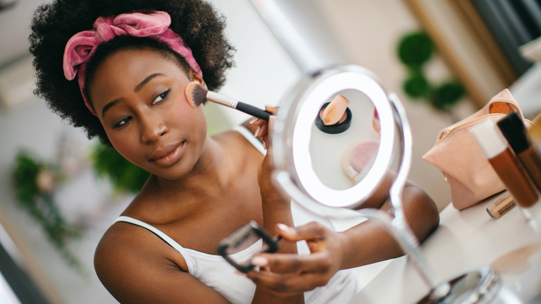 Woman applying blush in mirror