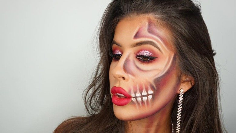 Girl with a half-face of skeleton makeup.