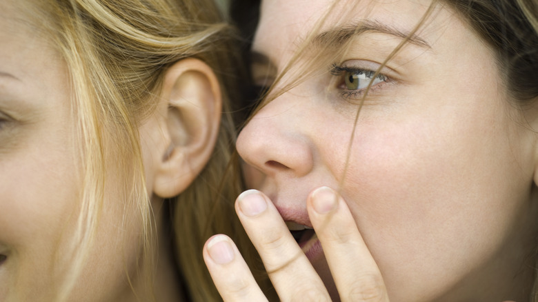 Woman whispering rumor to friend