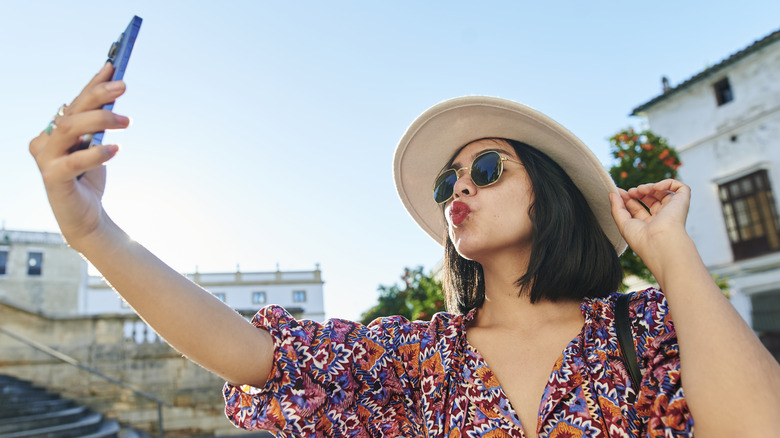 Woman taking duck-face phone selfie