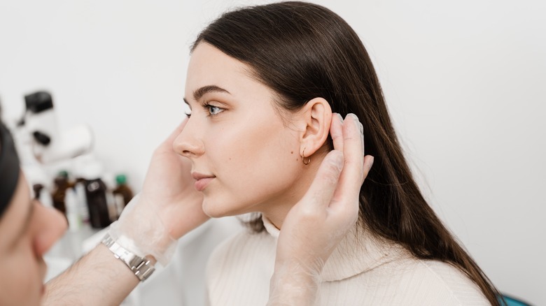 Plastic surgeon examines woman's face