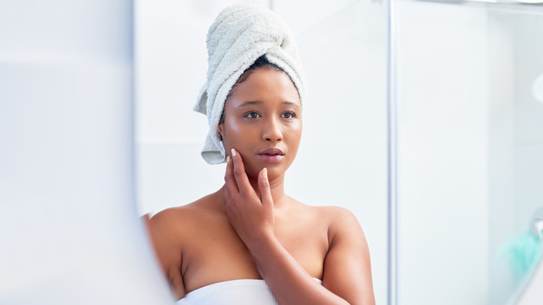 woman looking at face in mirror