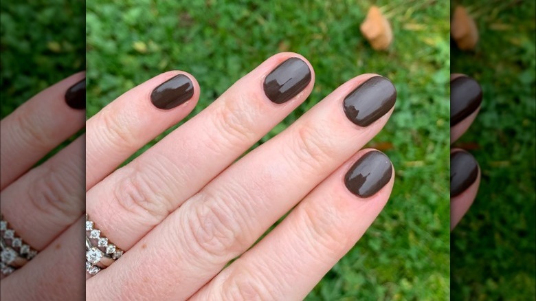 hand with dark brown nail polish