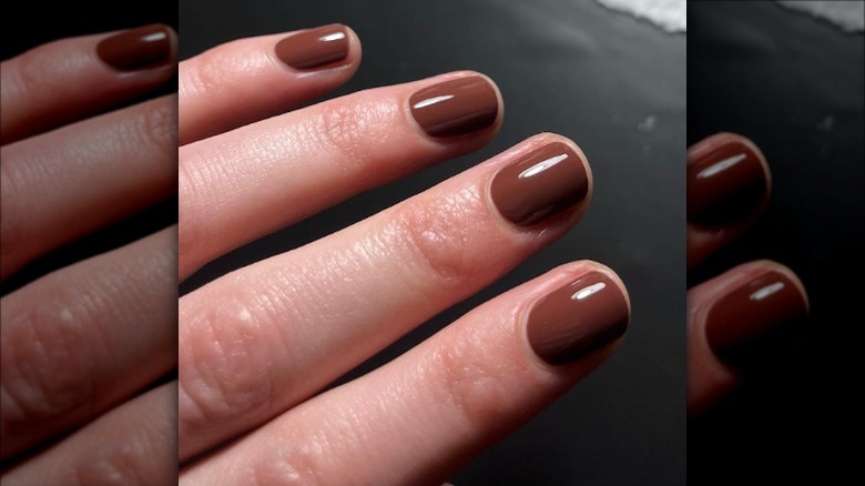 hand with dark brown nail polish