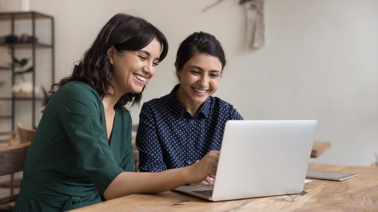 Two women sitting and talking with laptop