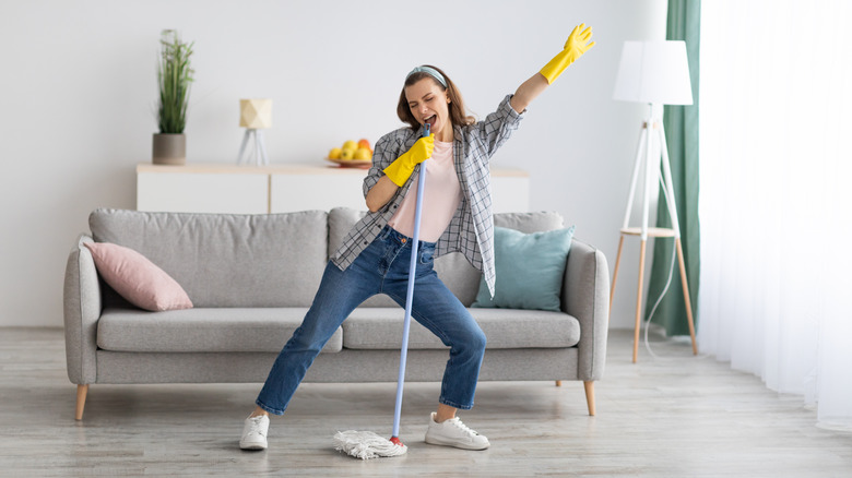 Woman dancing while cleaning floor