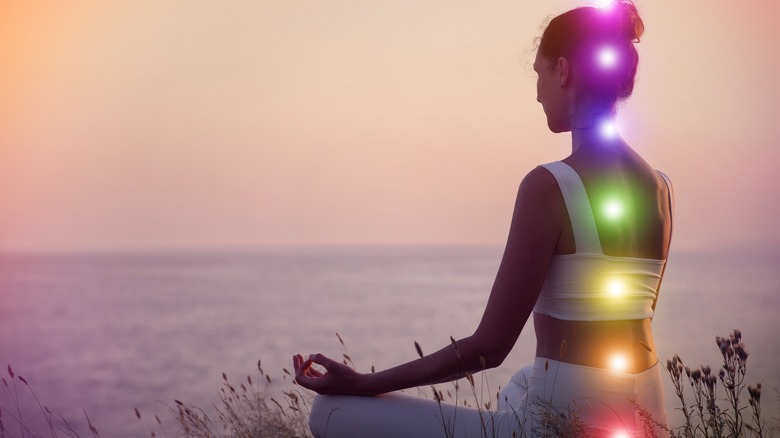 Woman meditating with glowing chakras