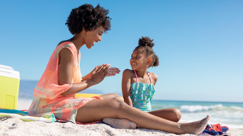 Woman applying sunscreen to daughter