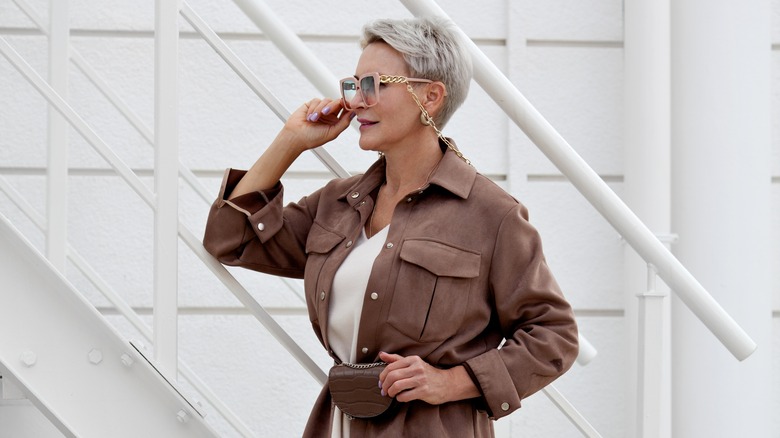 A woman wearing brown and white with pink sunglasses